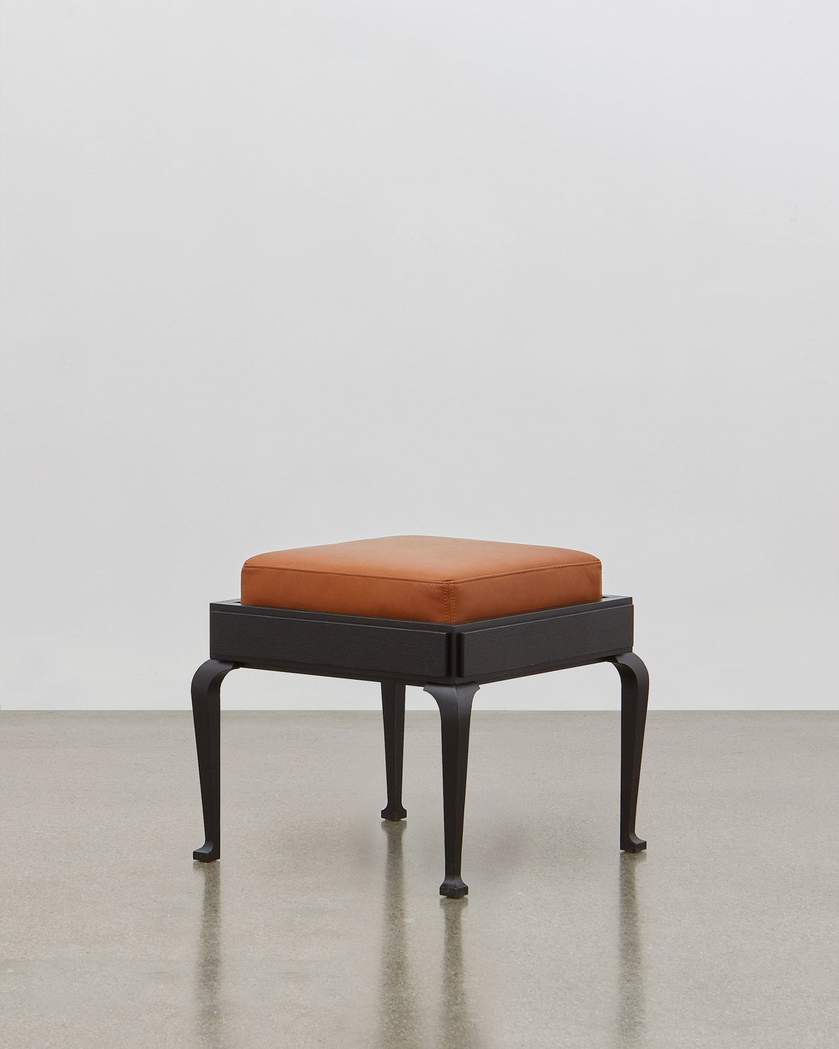 PH Stool by Poul Henningsen, Danish design classic (1920) A walnut upholstered stool standing on four angled black wooden legs.