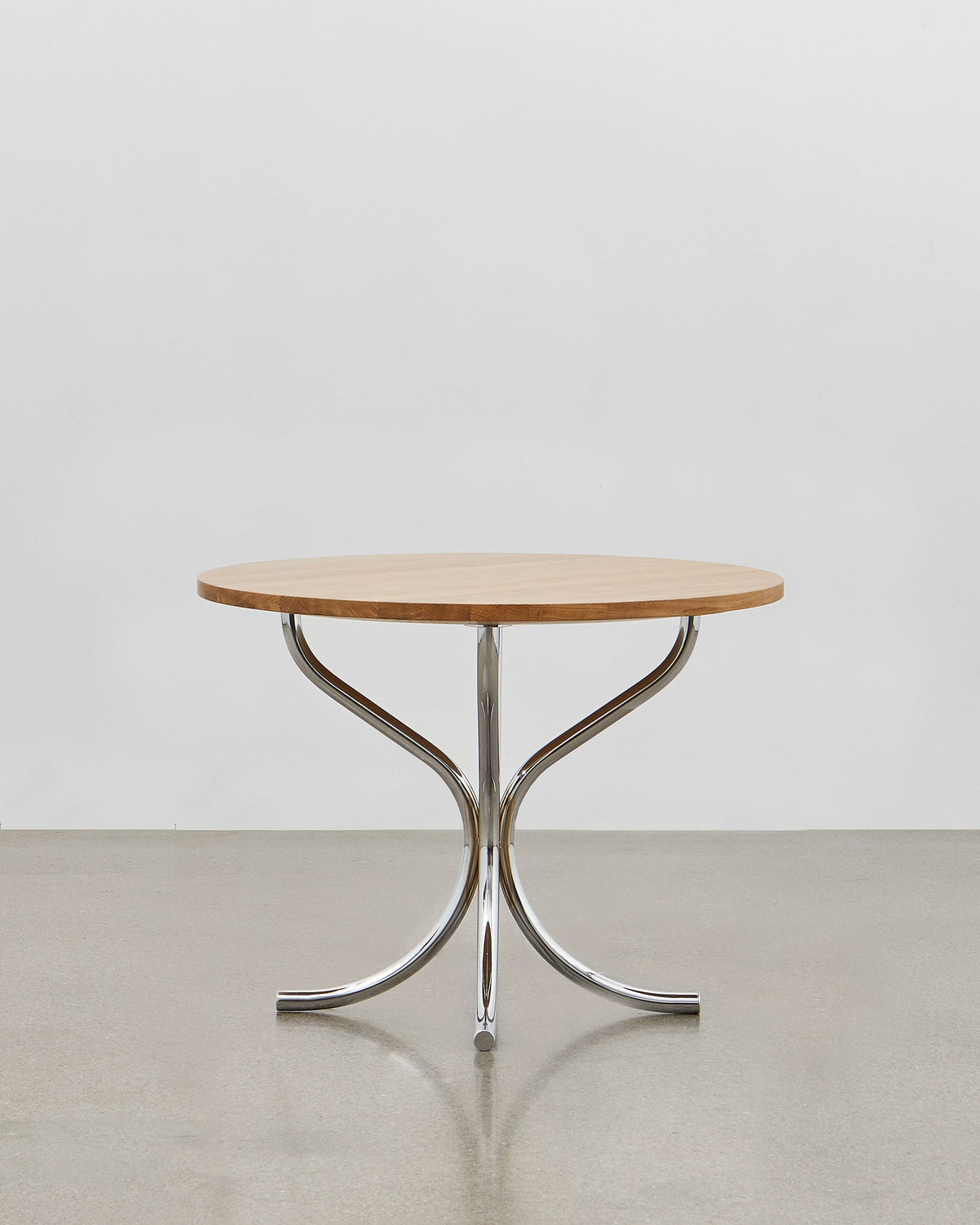 A round wooden lounge table with chrome metal legs, designed by Poul Henningsen.