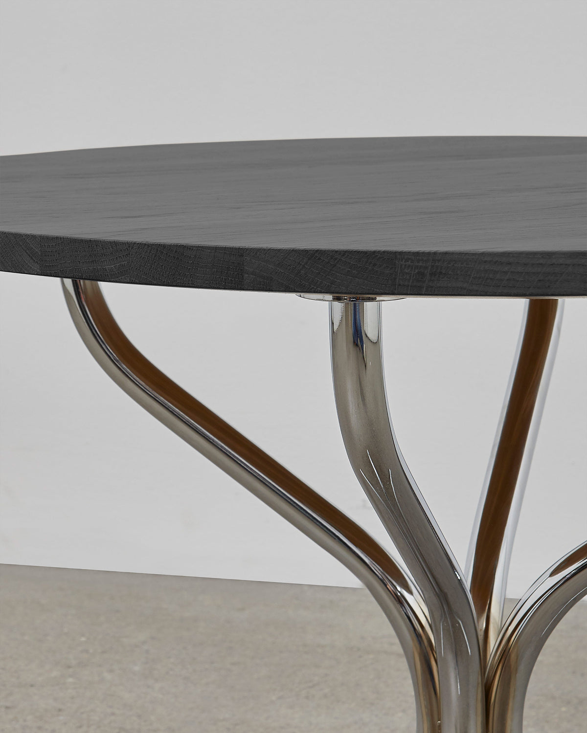 A round wooden lounge table with chrome metal legs, designed by Poul Henningsen.